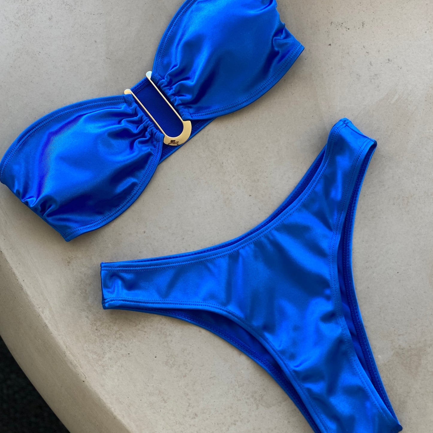 A shiny bandeau bikini designed to exude glamour on the beach. The bikini top features removable pads for style and comfort, along with a metal detail. Made from water-resistant material, the bikini is highly durable and not susceptible to color change or rusting, ensuring a fabulous look swim after swim.